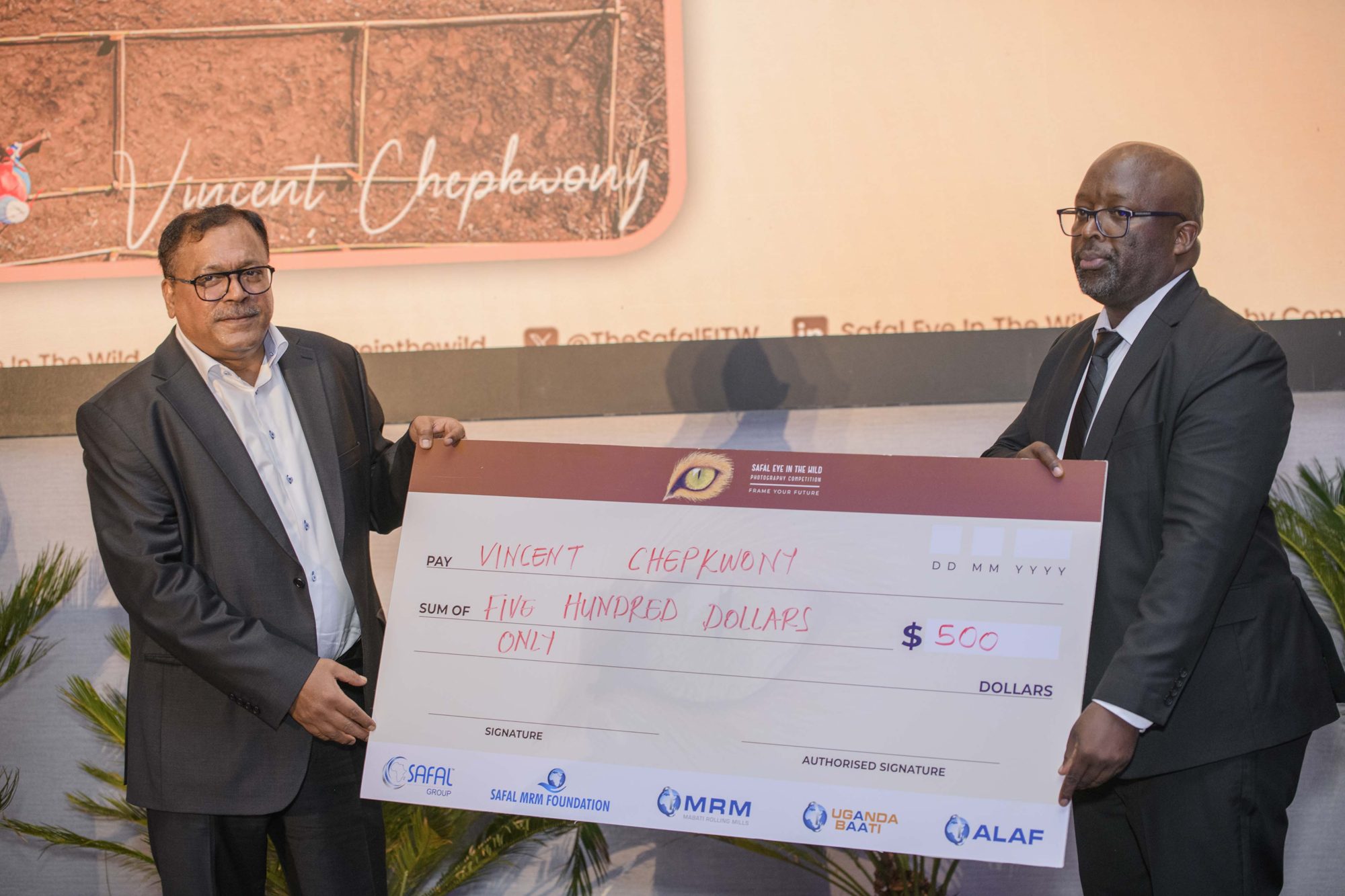 Vincent Chepkwony receiving a US$500 category prize cheque from a Safal Group executive at the SEIW gala.