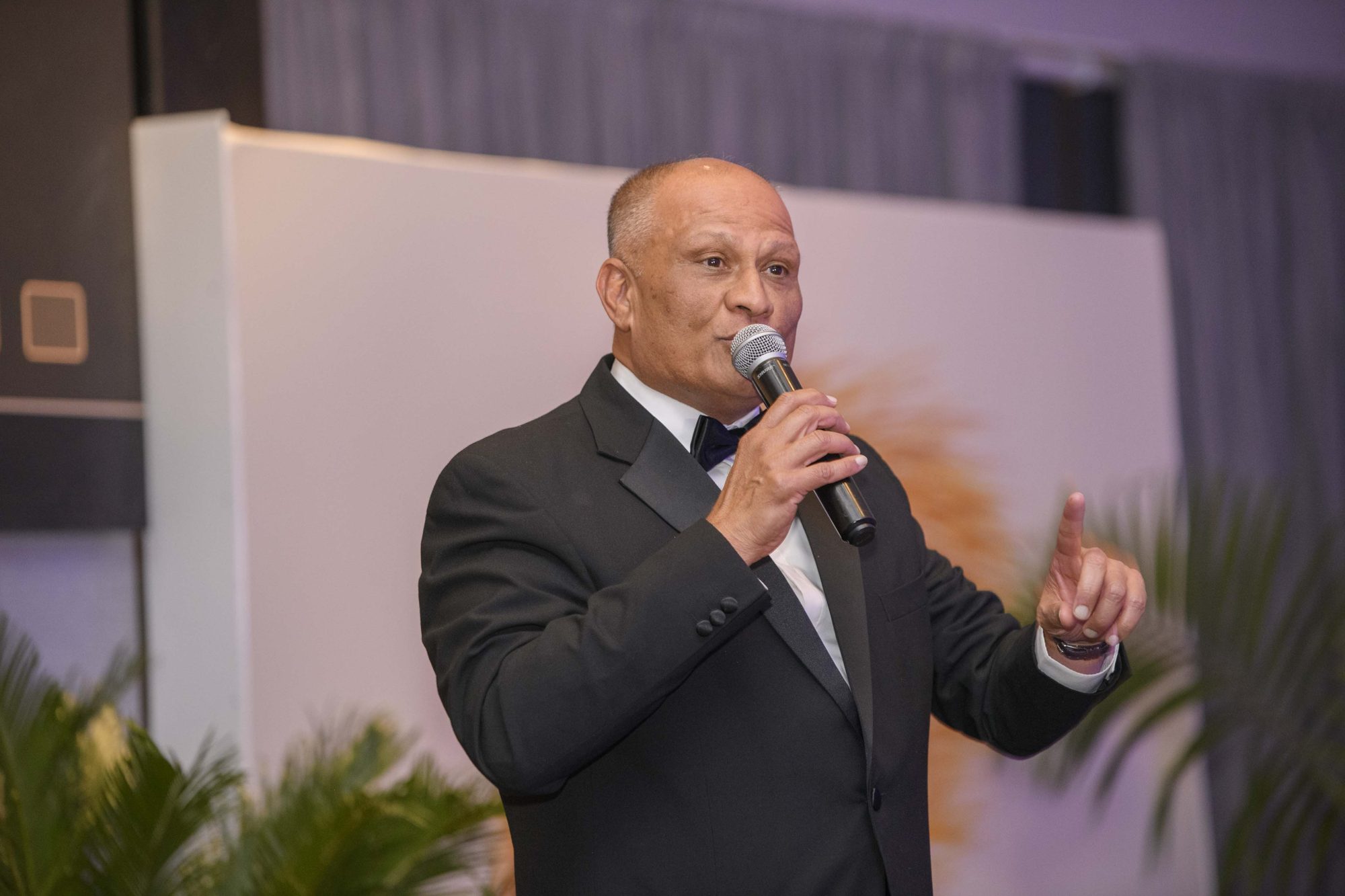 Safal Group executive in a tuxedo speaking into a microphone on stage at the SEIW gala.